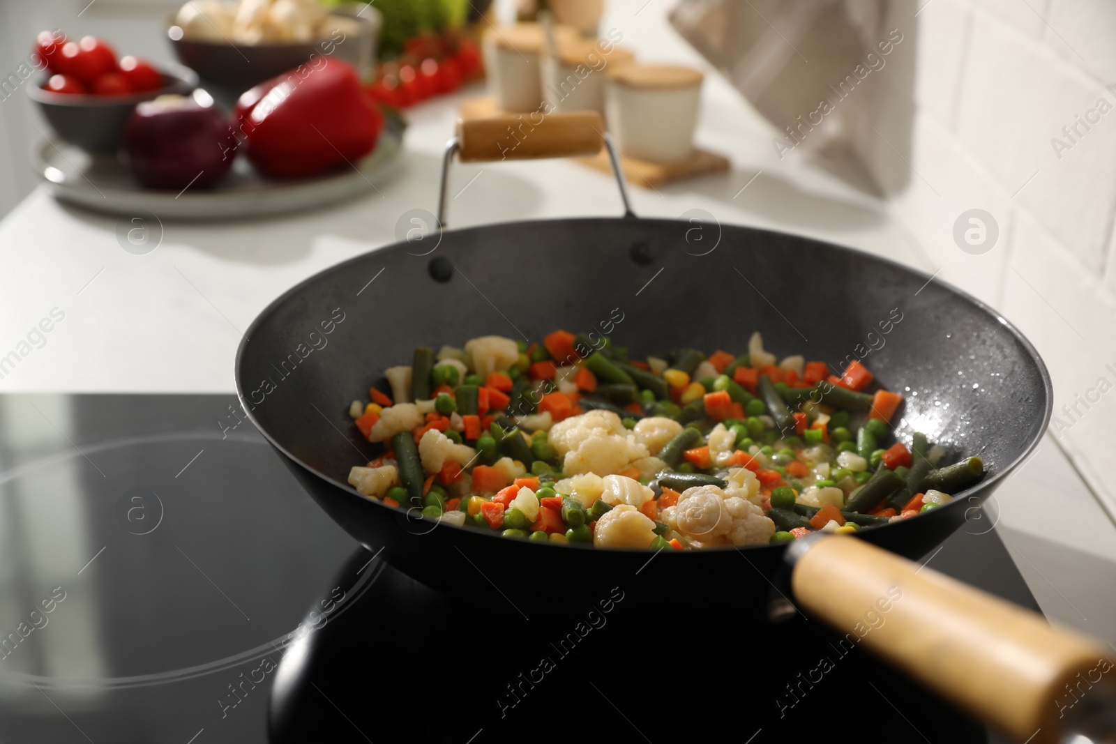 Photo of Frying pan with mix of fresh vegetables in kitchen