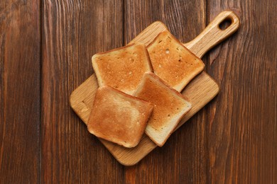 Photo of Slices of tasty toasted bread on wooden table, top view
