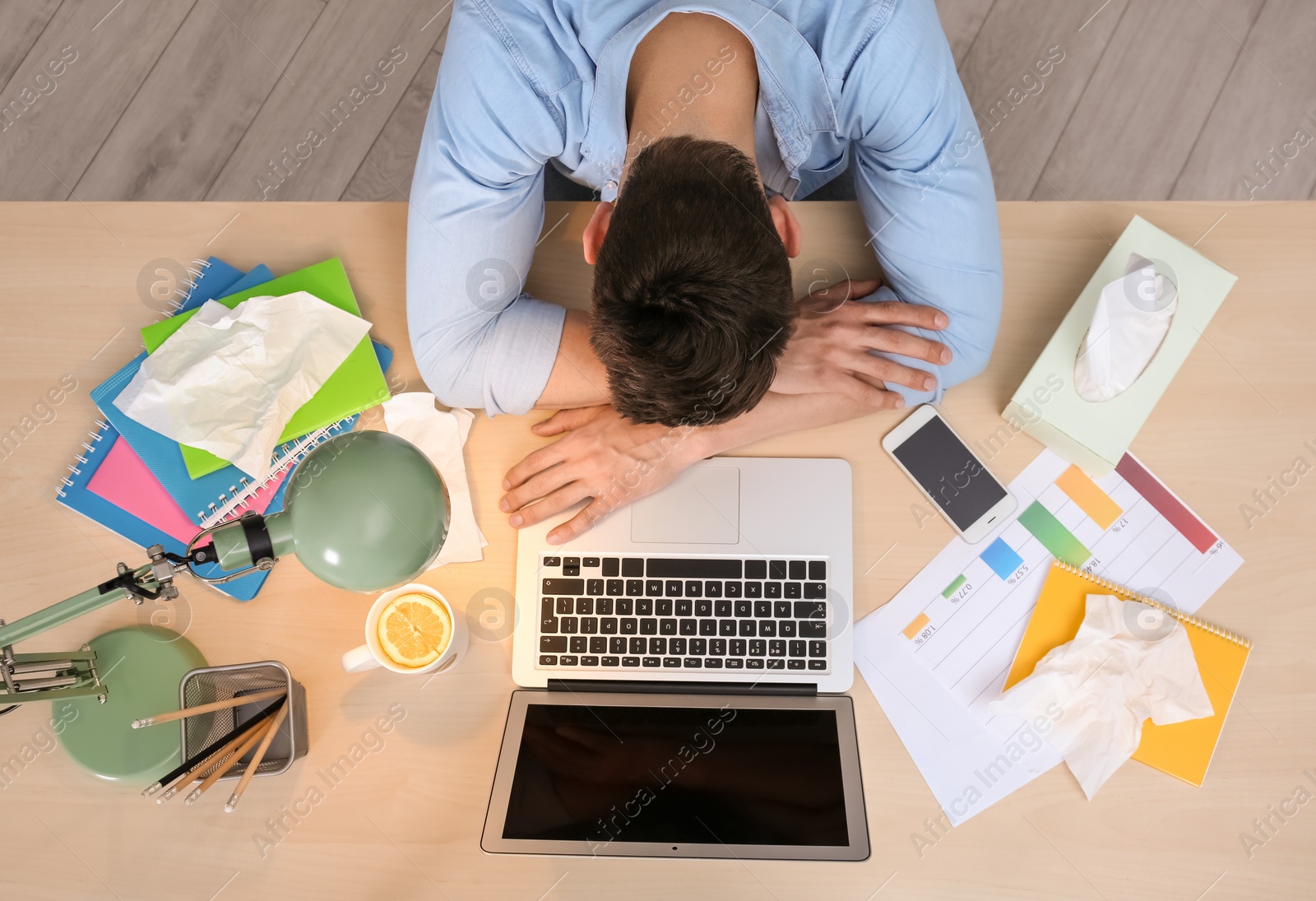 Photo of Exhausted man suffering from cold while working with laptop at table, top view