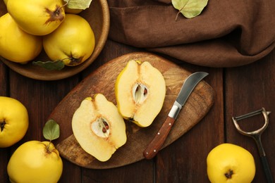 Photo of Tasty ripe quince fruits, peeler and knife on wooden table, flat lay