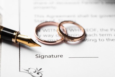 Photo of Marriage contract, fountain pen and wedding rings on table, closeup