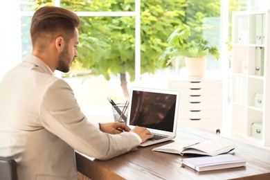 Photo of Man in office wear using laptop at table indoors