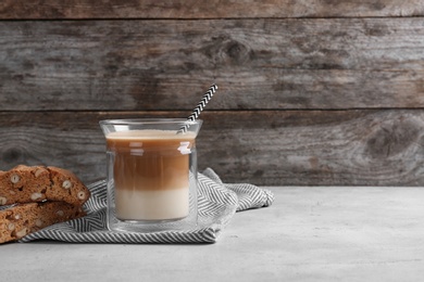 Photo of Glass with delicious coffee drink and cookie on table against wooden background. Space for text