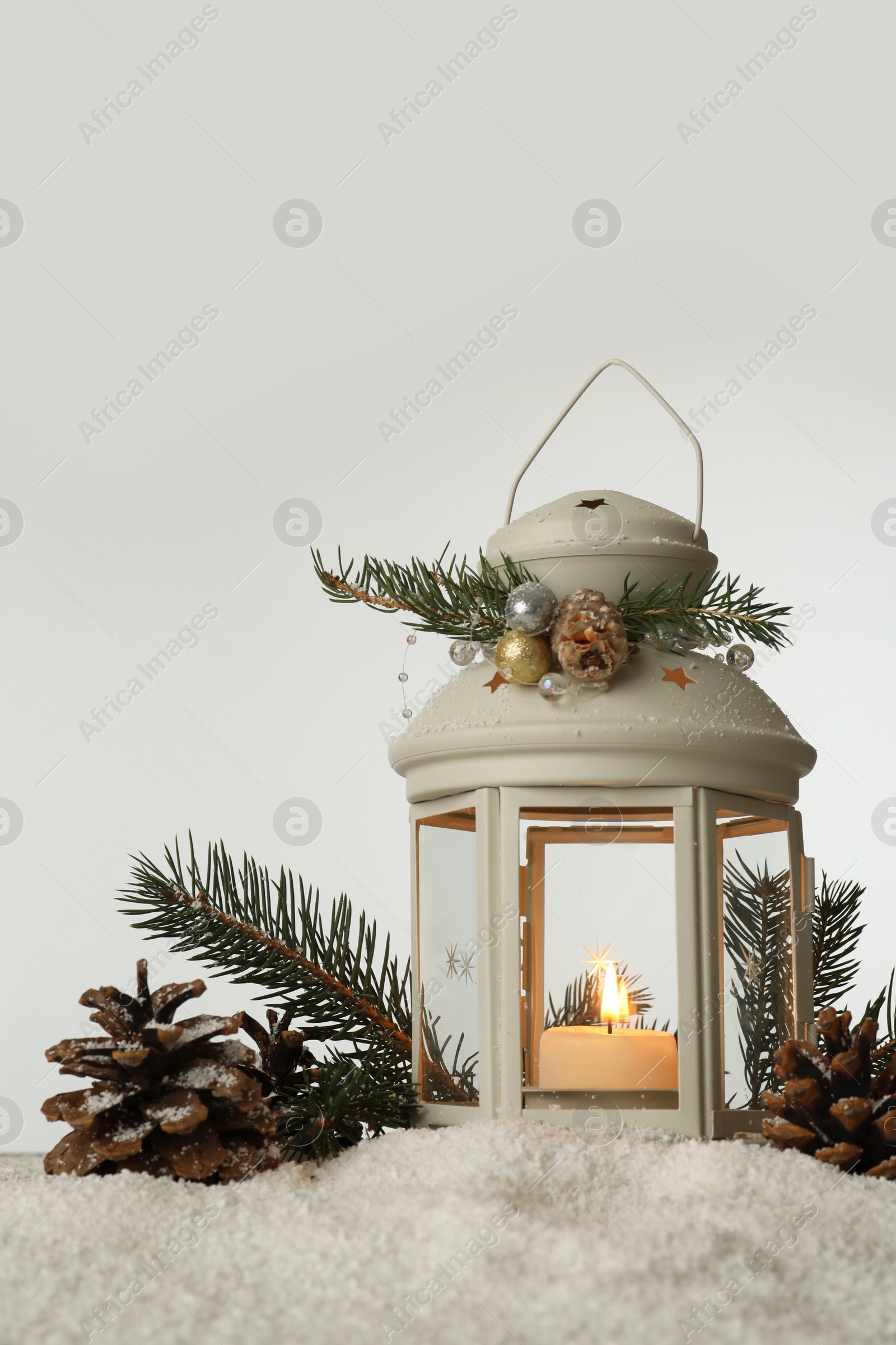 Photo of Decorative lantern and Christmas decor on snow against light grey background