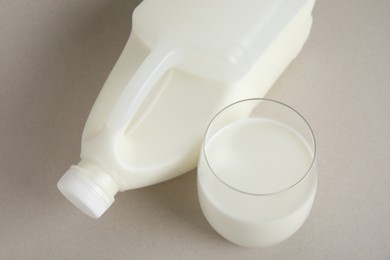 Photo of Gallon bottle and glass of milk on beige background