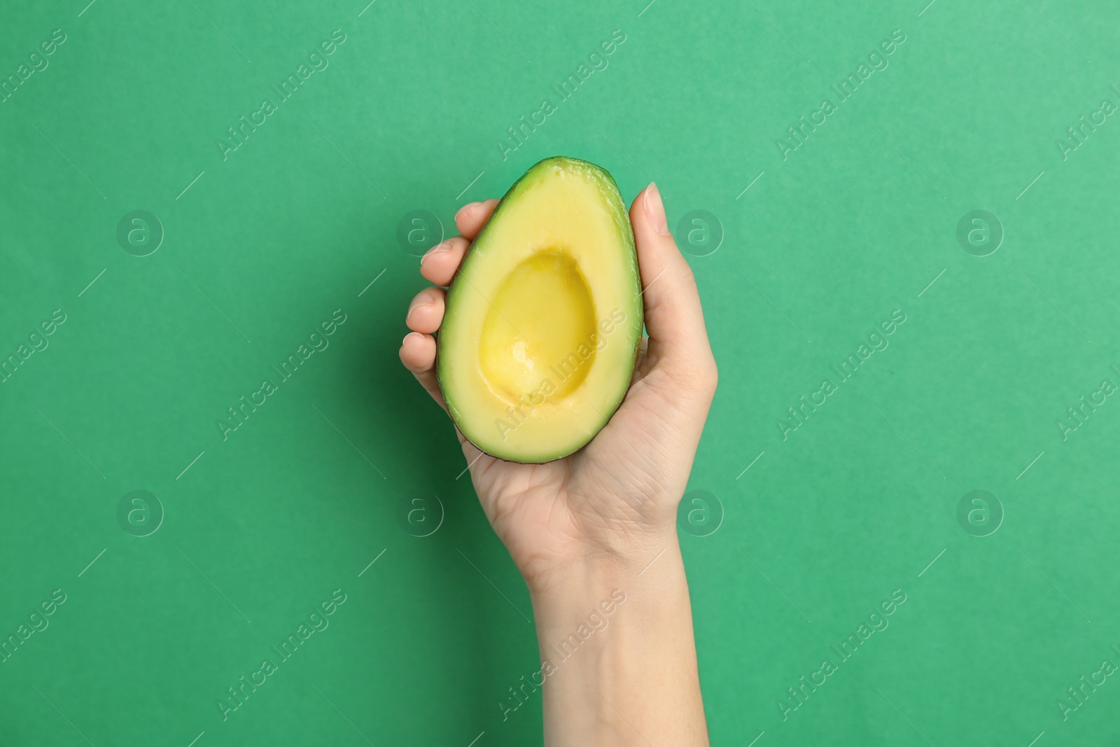 Photo of Woman holding ripe cut avocado on color background