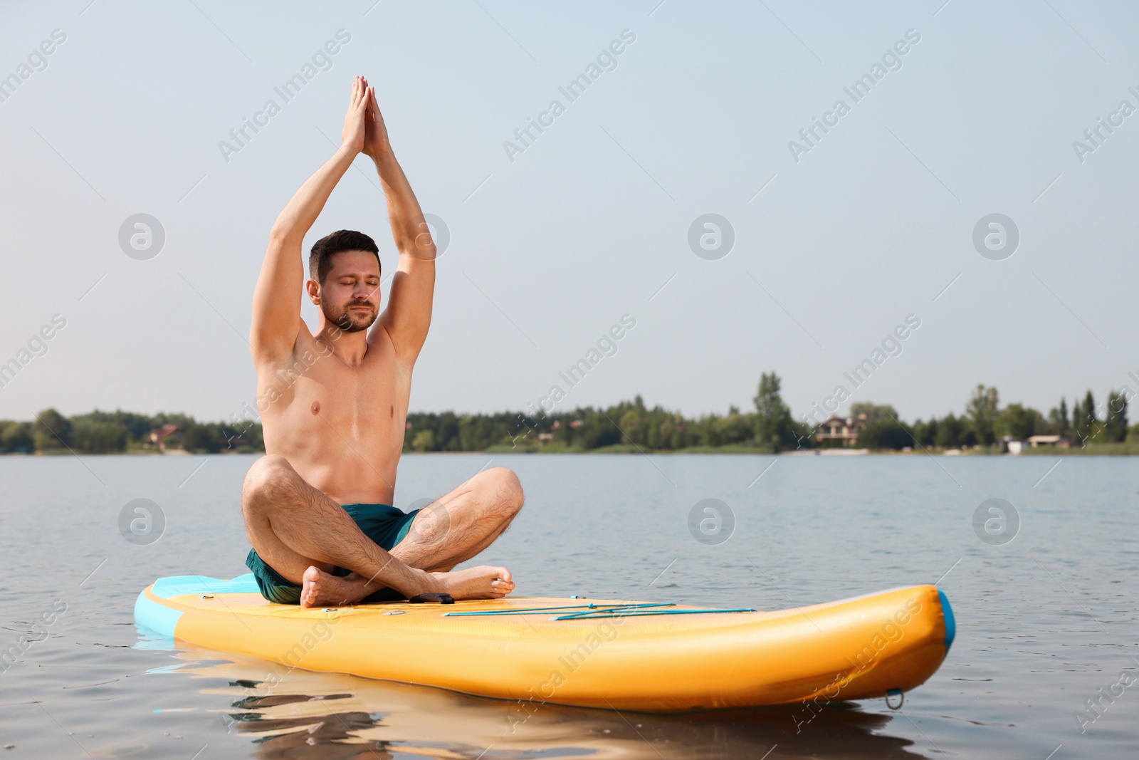 Photo of Man practicing yoga on SUP board on river