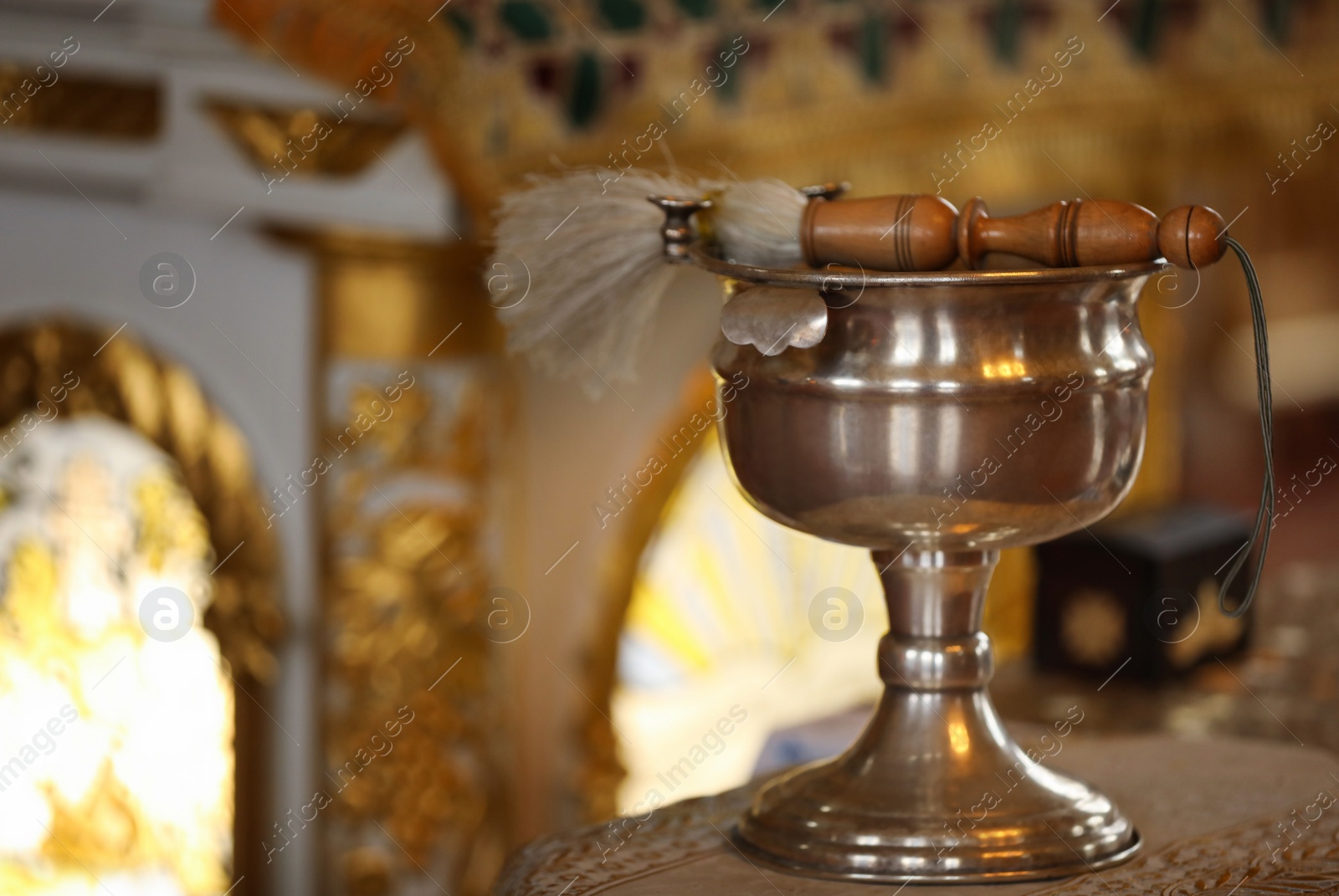 Photo of Silver vessel with holy water and brush on stand in church, space for text. Baptism ceremony