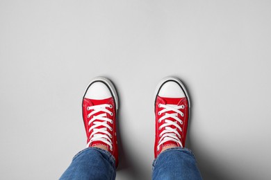 Woman in stylish gumshoes on light background, top view