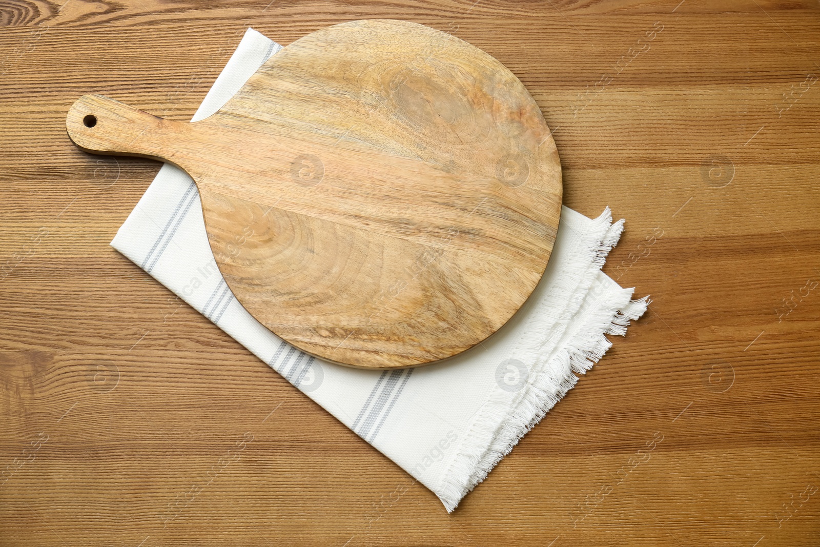 Photo of Empty wooden board and napkin on table, top view