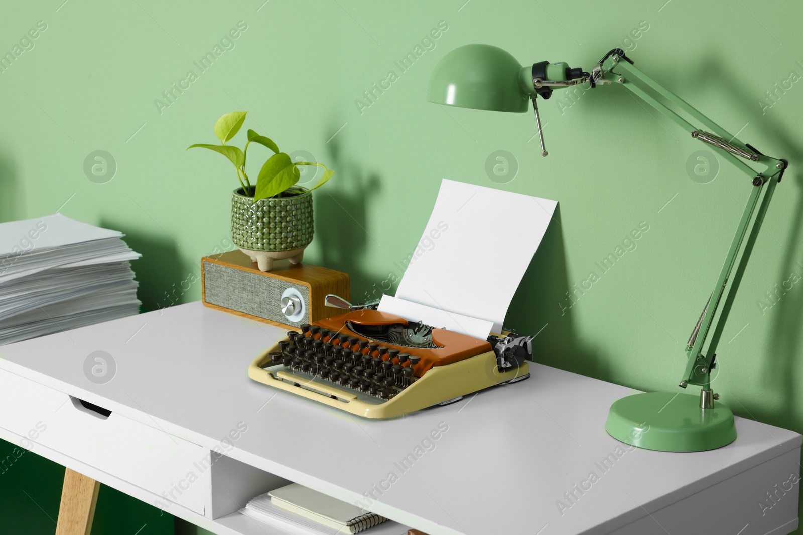 Photo of Writer's workplace with typewriter on wooden desk near pale green wall in room