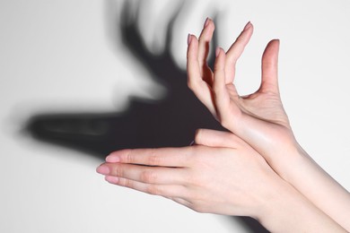 Shadow puppet. Woman making hand gesture like deer on light background, closeup