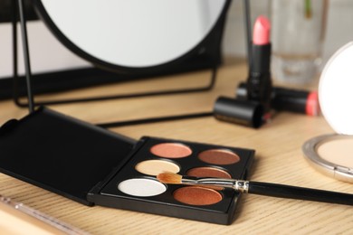 Photo of Eyeshadows and makeup brush on dressing table, closeup