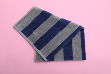 Photo of Folded striped beach towel on pink background, top view