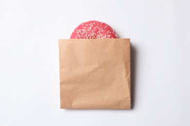 Photo of Paper bag with glazed doughnut on white background, top view. Space for design