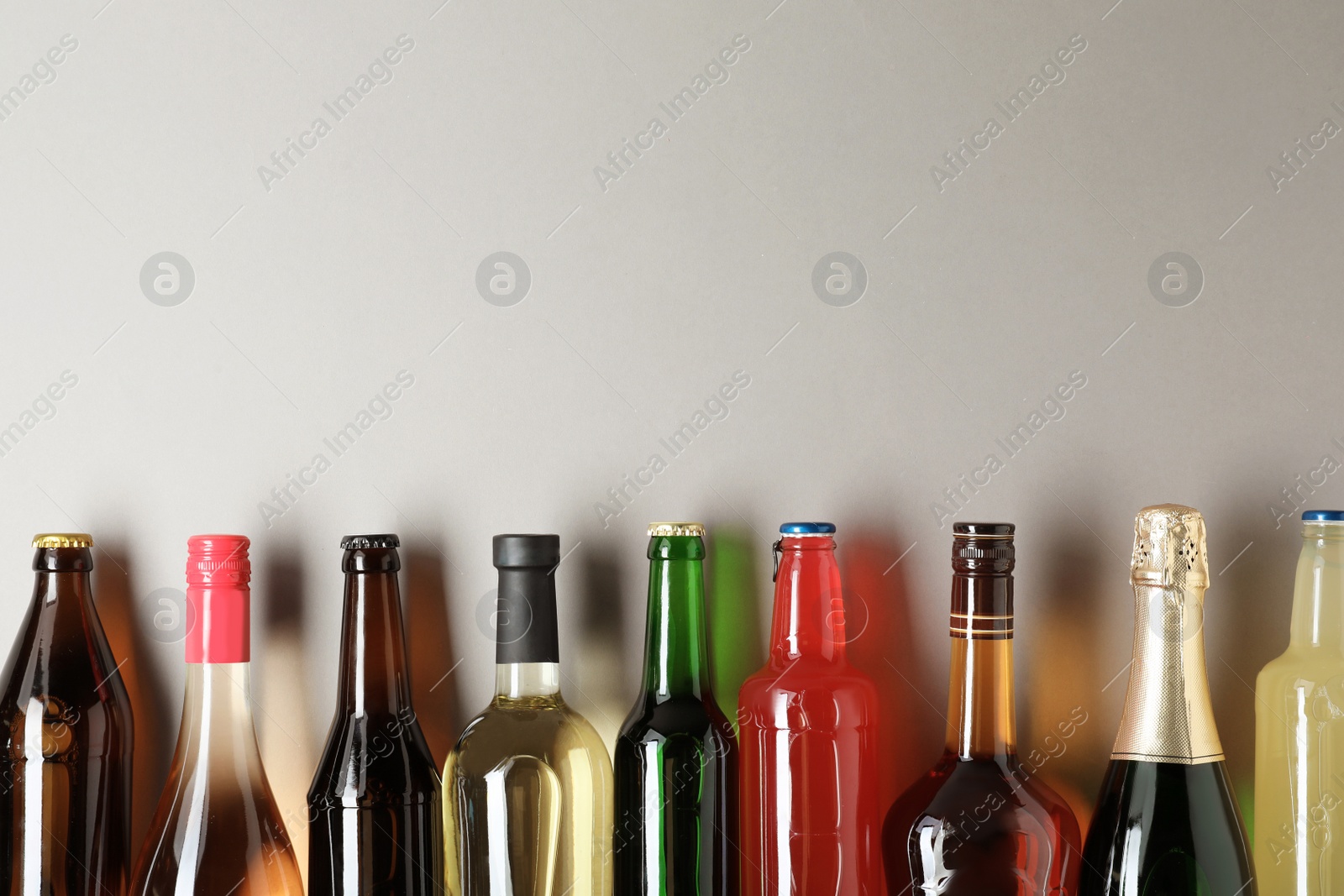 Photo of Bottles with different alcoholic drinks on light background, top view. Space for text