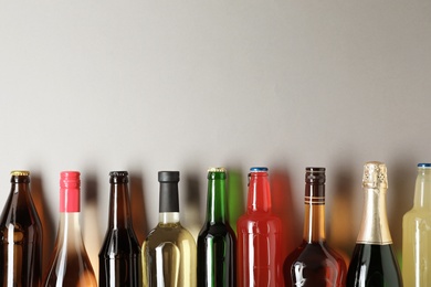 Photo of Bottles with different alcoholic drinks on light background, top view. Space for text