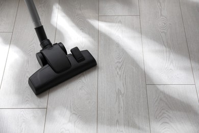 Photo of Brush of modern vacuum cleaner on floor indoors. Space for text