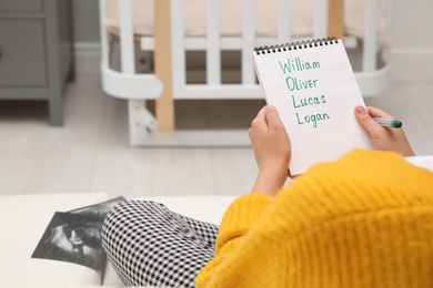 Photo of Pregnant woman with baby names list sitting on sofa, closeup