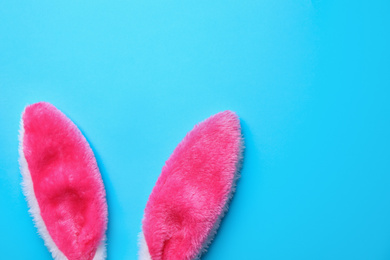 Photo of Easter bunny ears on light blue background, top view. Space for text