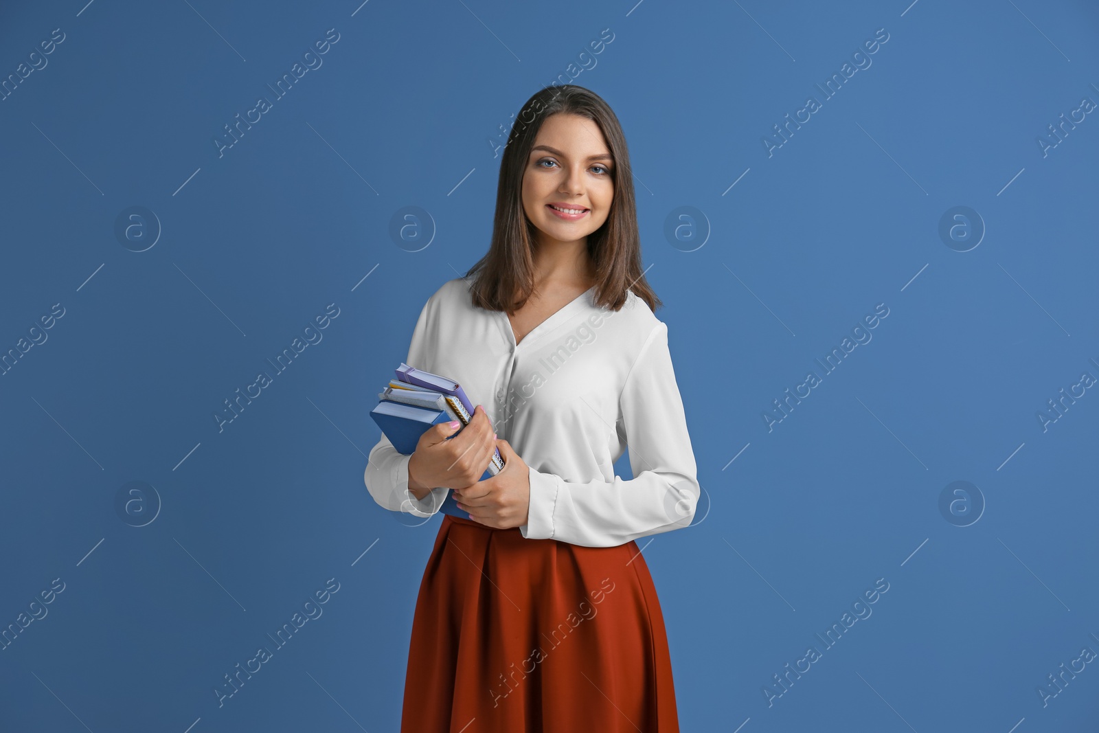 Photo of Portrait of female teacher with notebooks on color background