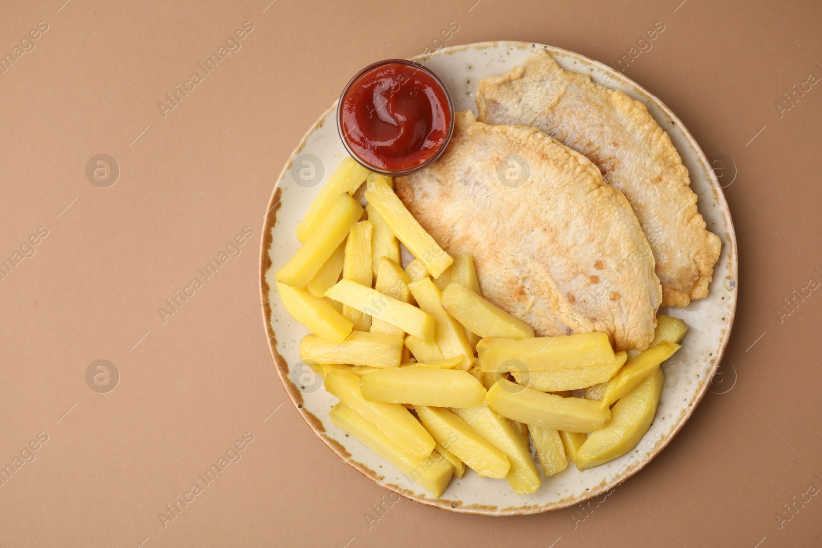 Photo of Delicious fish and chips with ketchup on light brown table, top view. Space for text