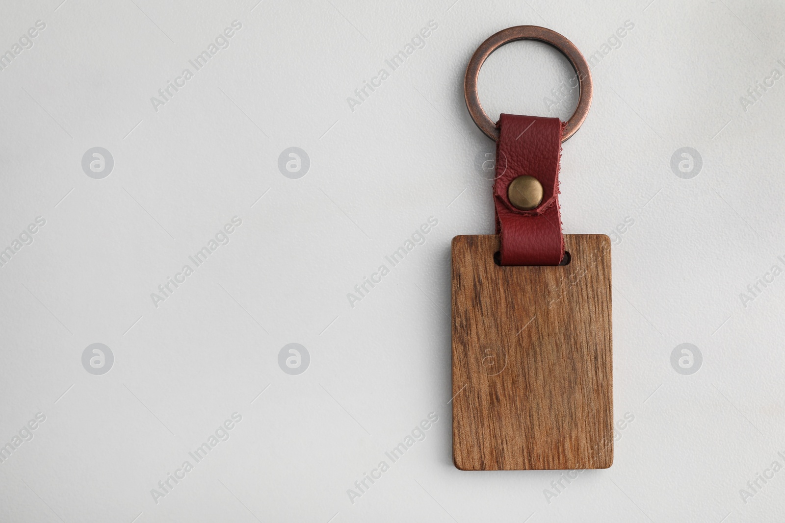Photo of Wooden keychain with Ukrainian coat of arms on white marble table, top view. Space for text
