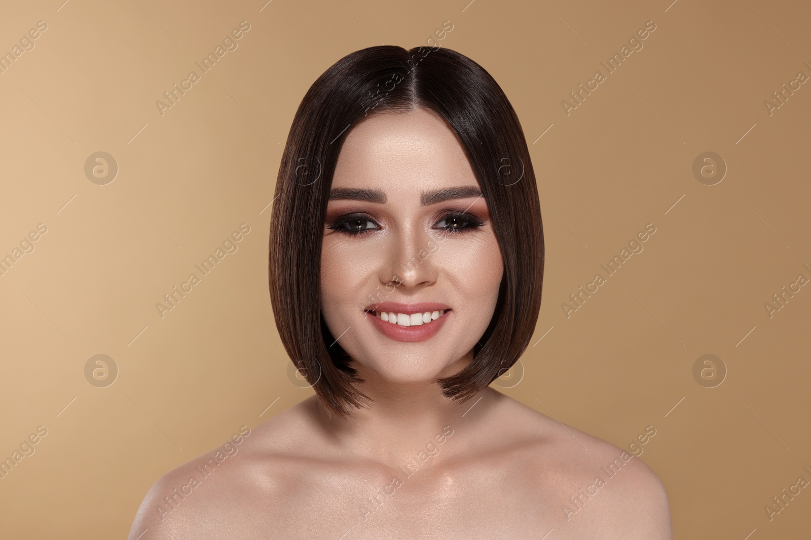 Image of Portrait of pretty young woman with brown hair smiling on beige background