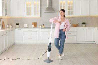 Photo of Happy woman with steam mop in kitchen at home