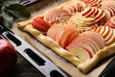 Photo of Baking tray with uncooked apple galette on wooden table, closeup