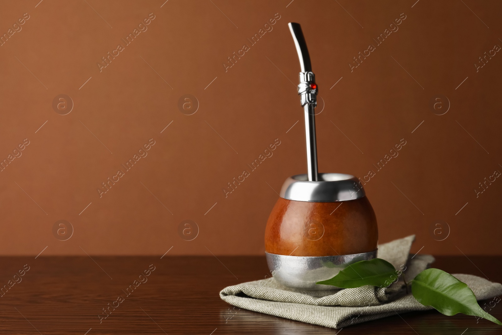 Photo of Calabash with mate tea and bombilla on wooden table. Space for text