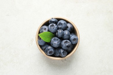 Photo of Tasty fresh blueberries in bowl on light table, top view