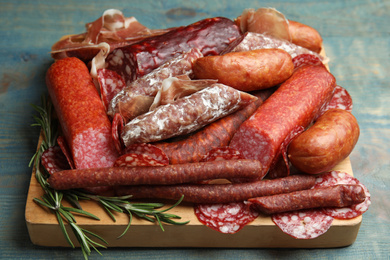 Photo of Different types of sausages served on light blue wooden table, closeup