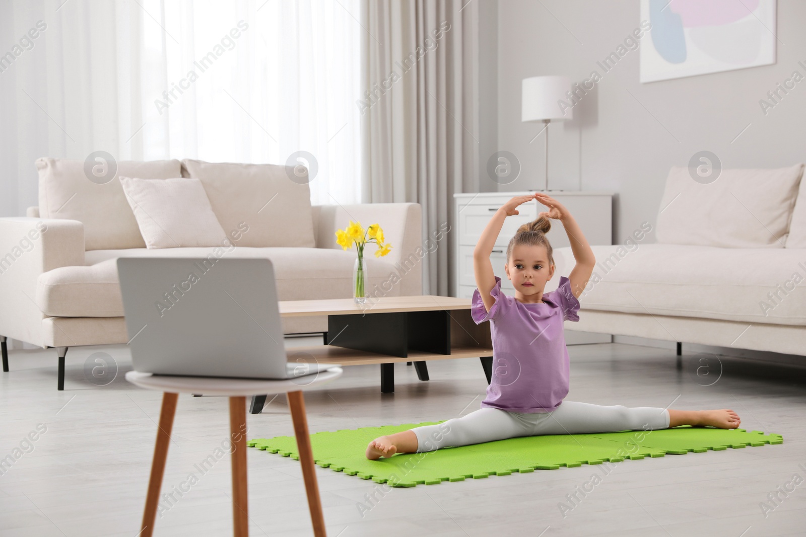 Photo of Cute little girl warming up before online dance class at home