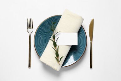 Photo of Stylish table setting with cutlery, blank card and eucalyptus leaves on white background, flat lay