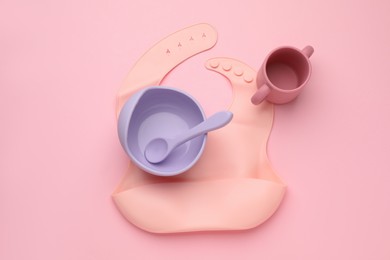 Photo of Baby feeding accessories and bib on pink background, flat lay