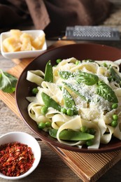 Delicious pasta with green peas, fresh basil and cheese on wooden table, closeup