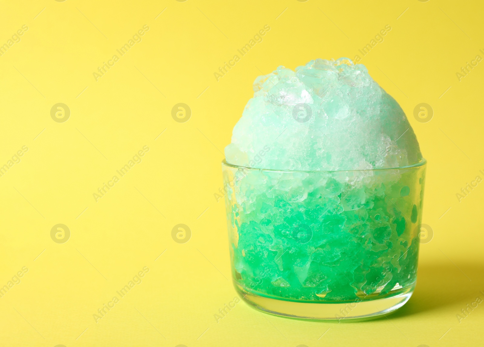 Photo of Shaving ice in glass dessert bowl on yellow  background, closeup. Space for text