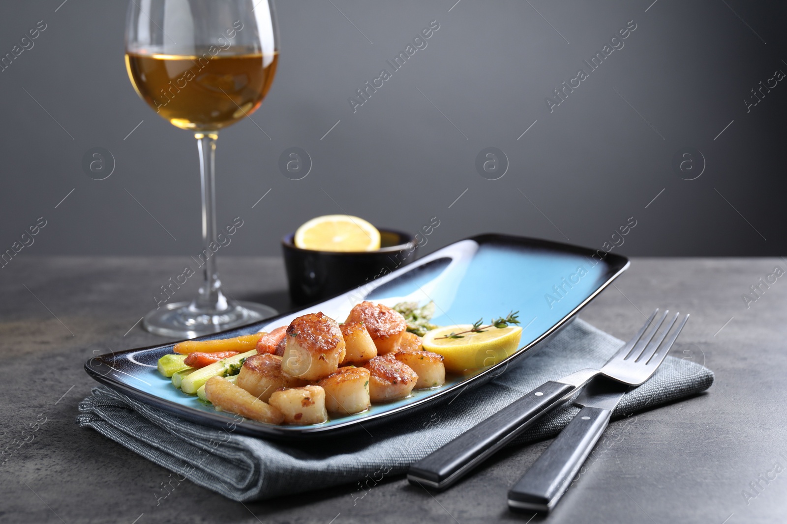 Photo of Delicious fried scallops with asparagus served on grey table