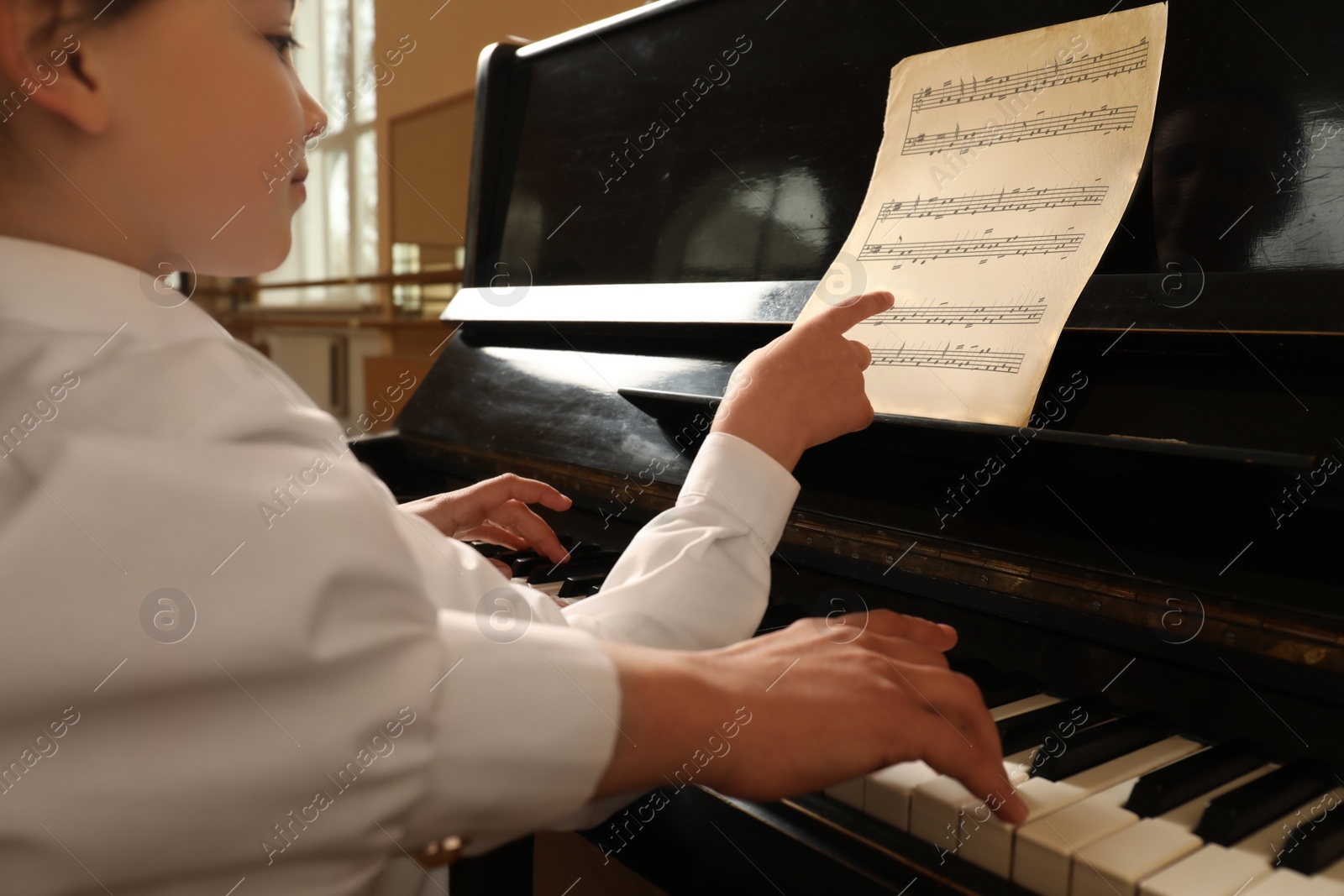 Photo of Young woman with child playing piano, closeup. Music lesson