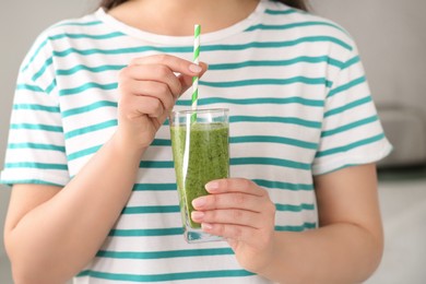Photo of Woman holding glass with delicious smoothie on blurred background, closeup