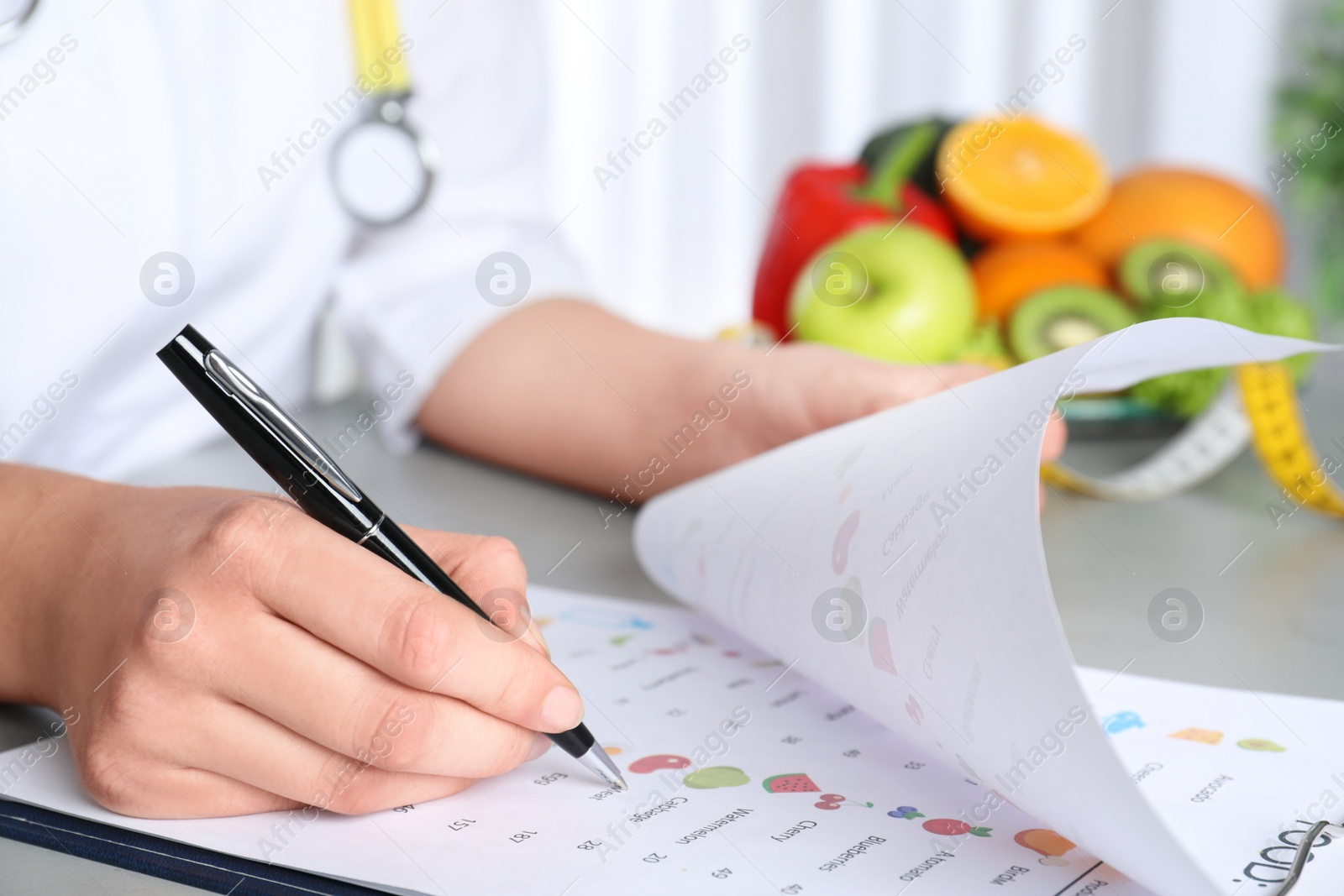 Photo of Female nutritionist with list of products at table, closeup