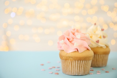 Tasty cupcakes on table against blurred lights, space for text. Valentine's Day celebration