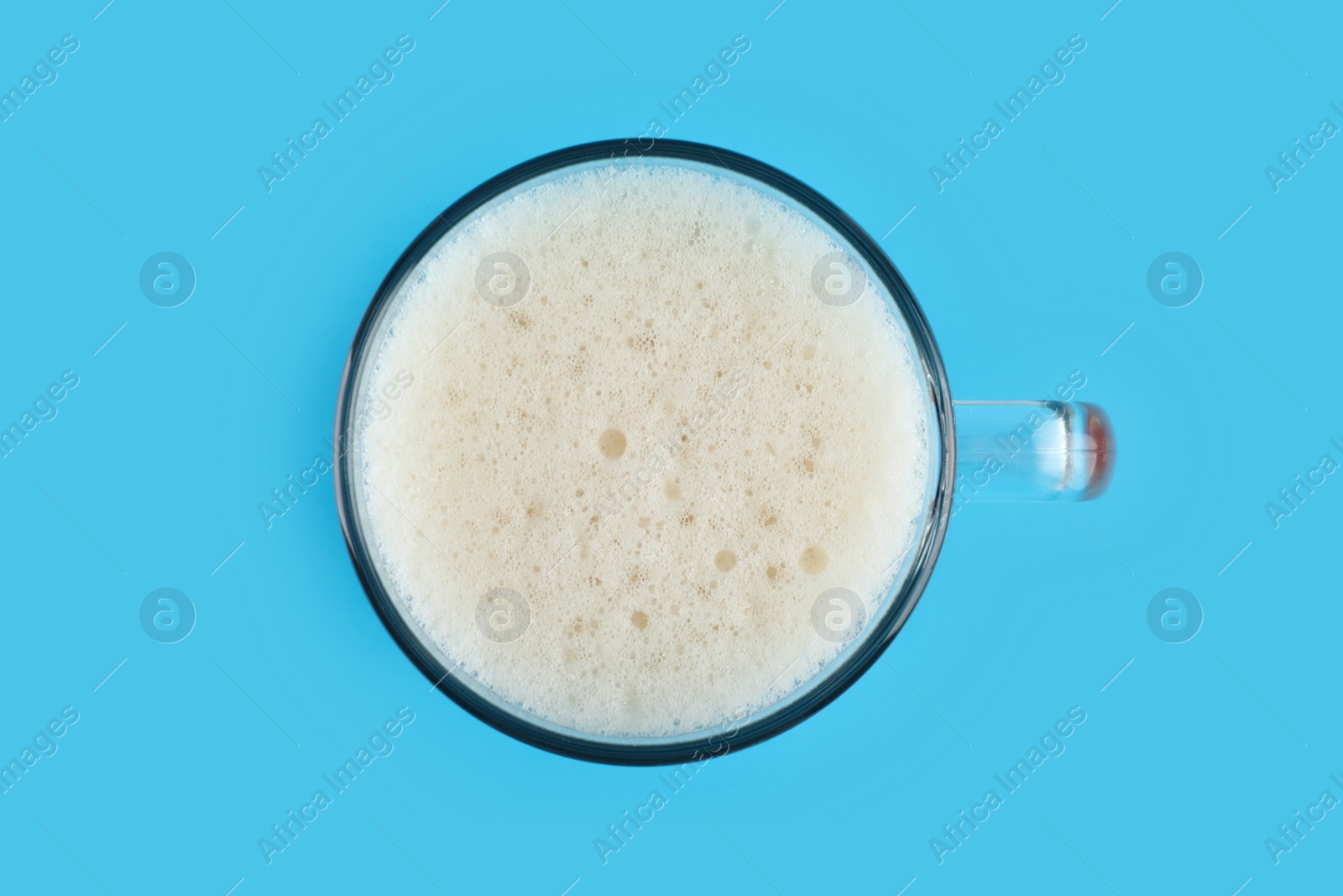 Photo of Delicious homemade kvass in glass mug on light blue background, top view