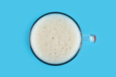 Photo of Delicious homemade kvass in glass mug on light blue background, top view