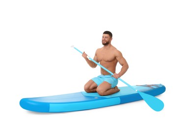 Handsome man with paddle on blue SUP board against white background