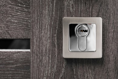 Metal keyhole on dark wooden door, closeup