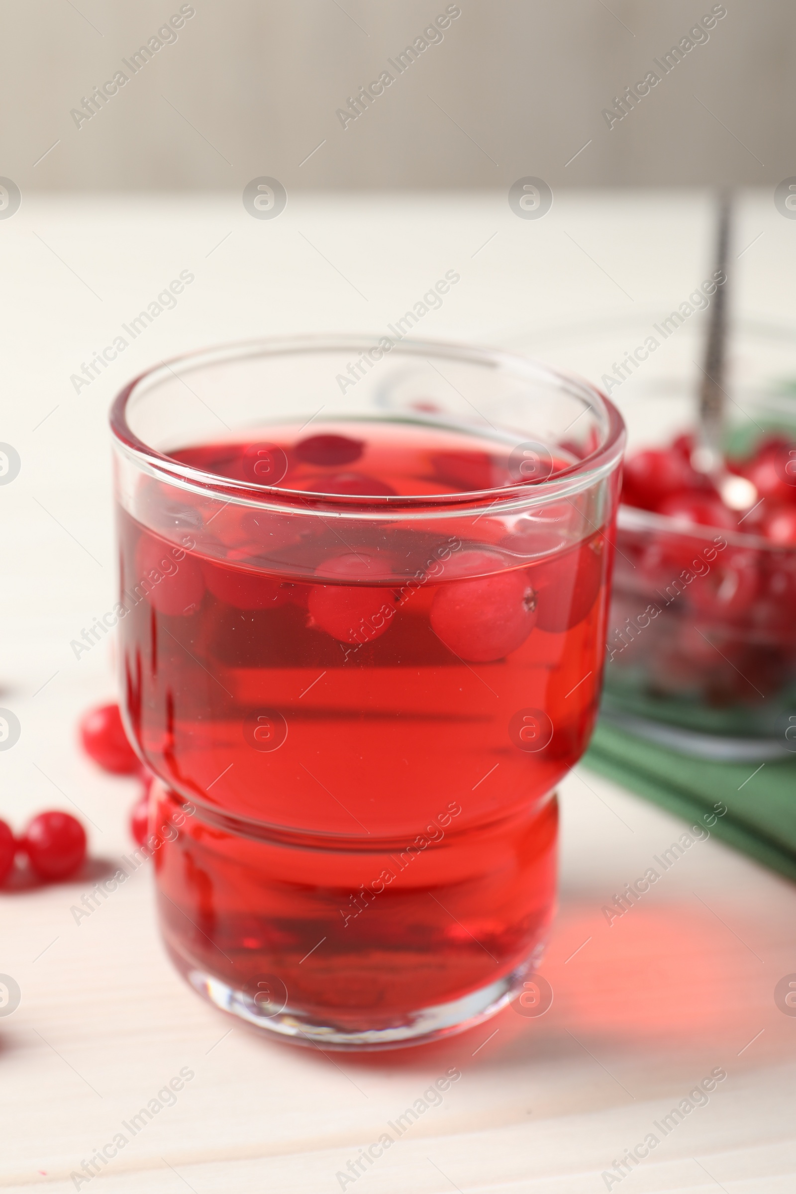 Photo of Tasty cranberry juice in glass and fresh berries on white wooden table, closeup