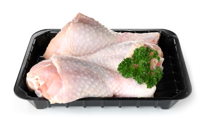 Photo of Plastic container with raw chicken drumsticks and parsley on white background. Fresh meat