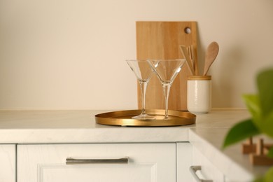 Elegant clean empty martini glasses on light countertop in kitchen, space for text